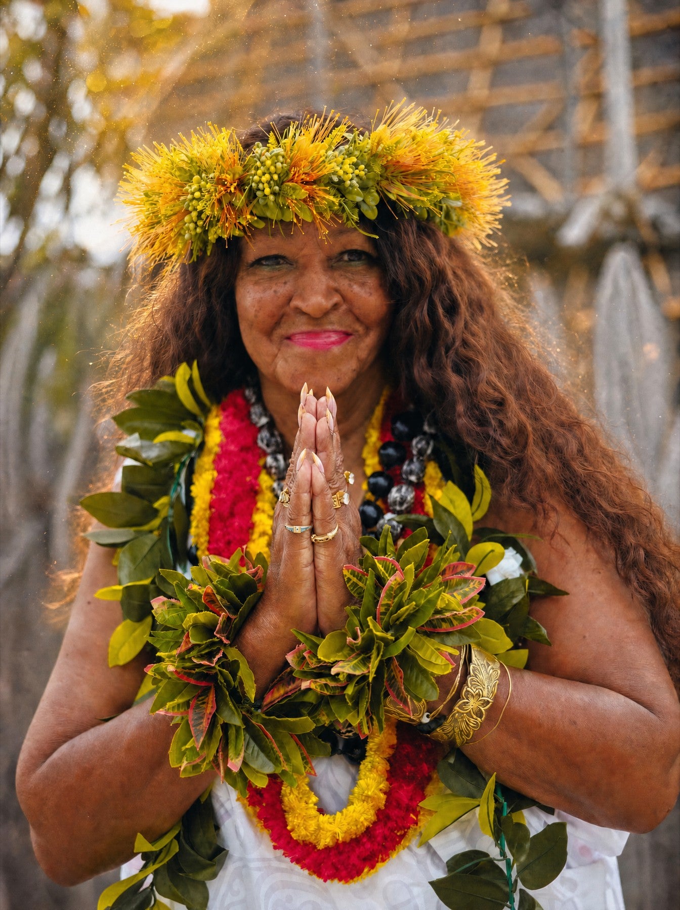 Kahu Kāhealani with her hands together in prayer, wearing a haku lei